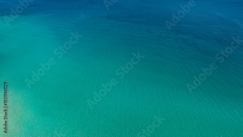 Aerial view of the crystalline sea surface. The water's colors range from blue to turquoise. Ideal for backgrounds, patterns, and textures of dreamy seas.