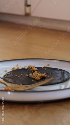Leftovers on black porcelain plate with golden fork on cafe wooden countertop. Breakfast with tasty cappuccino and cake in coffee shop vertical video