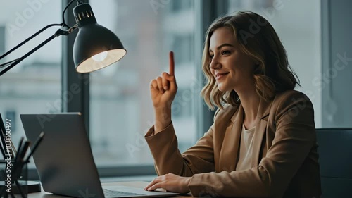 Young woman working on laptop and gesturing while sitting indoors  