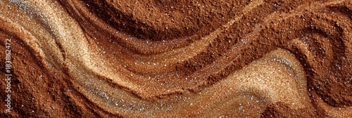 Swirled cinnamon powder forms soft textured waves with scattered sugar crystals creating a warm, abstract pattern in rich brown and golden tones
