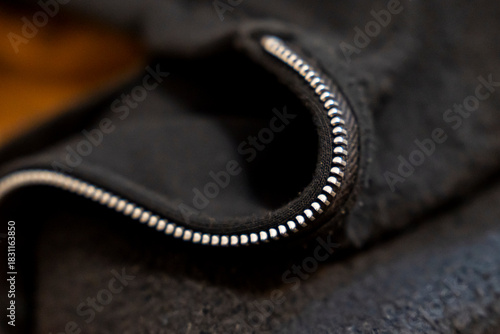 Close-up of a zipper on a black fabric showcasing intricate details. This image captures the texture and design of clothing materials, suitable for fashion contexts.