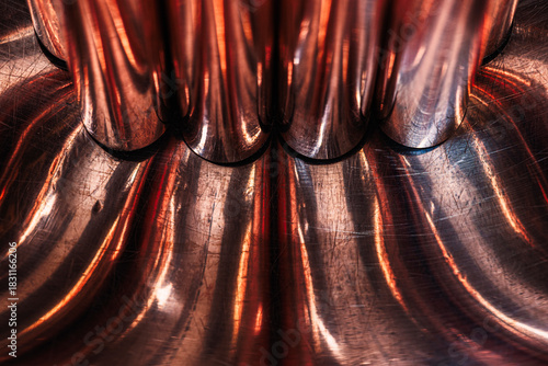 Copper rods on a convex metal surface, forming abstract curves, a concept of the fluidity of non-ferrous metals