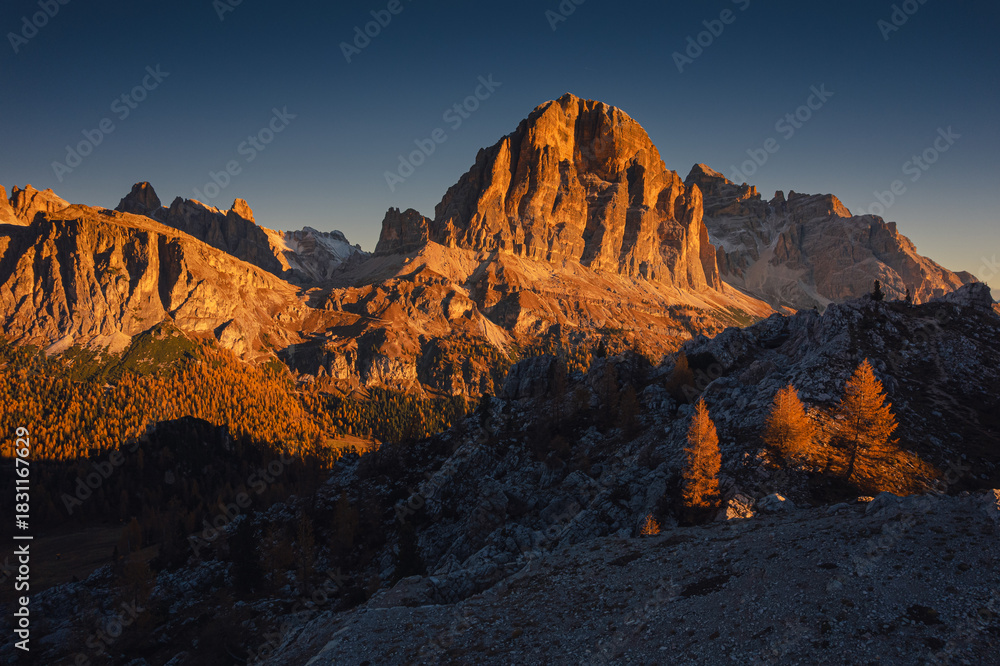 Naklejka premium Autumn morning near Cinque Torri and Tofana in the Dolomites — drone view of golden light, crisp air, and rugged peaks above quiet valleys. A serene, colorful mountain landscape. 