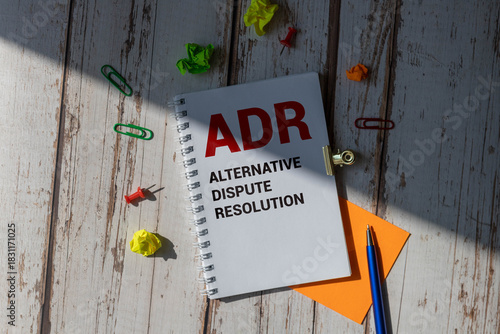 ADR Alternative Dispute Resolution is written in a white notepad near a calculator