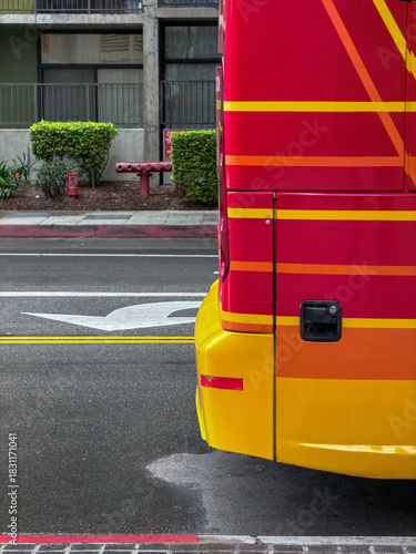 Close-up of red and yellow painted bus or vehicle panel on city street with crosswalk