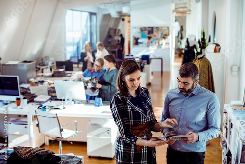 Adult coworkers focused on design review in modern office