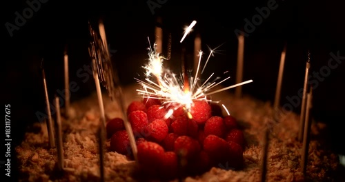 Illuminating treat a miniature cake with raspberries and sparking light sticks making a nighttime celebration special