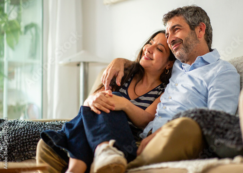Loving couple cuddling and smiling together while relaxing on couch at home