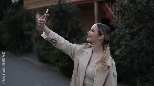 A young woman with a smartphone in her hand is talking on a video call or blogging online while traveling. Social media concept.