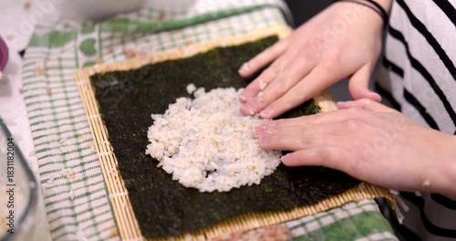 Learning how to make homemade sushi rolls on a bamboo mat with nori seaweed and short grain rice