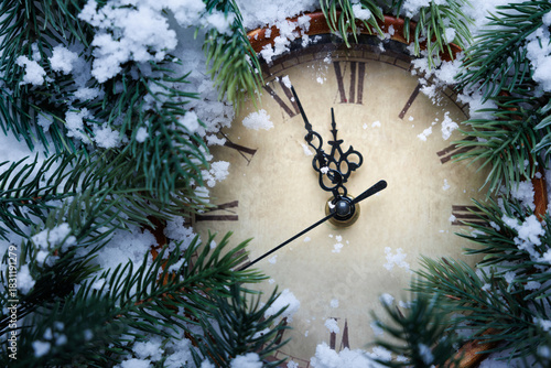 Vintage clock and fir tree branches in the snow.
