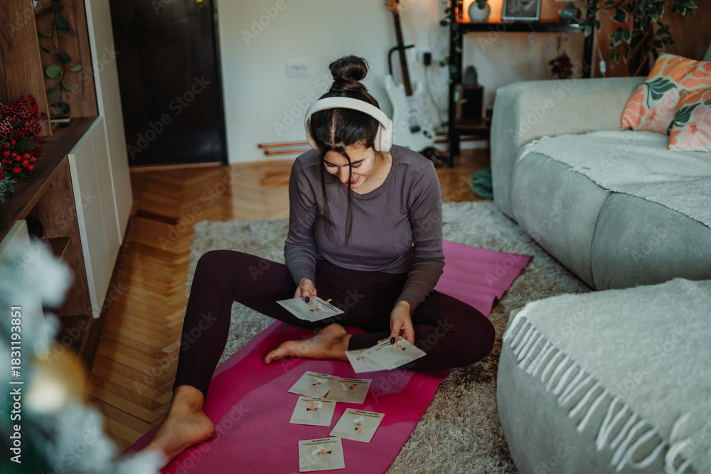 Obraz premium Woman choosing home yoga workout routine cards