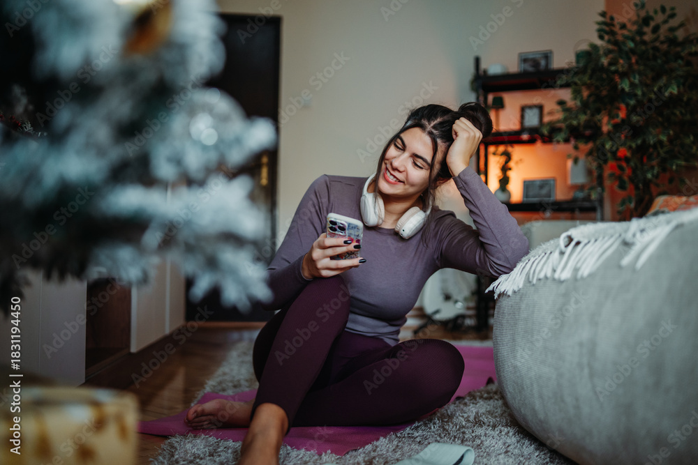 Obraz premium Woman relaxing at home, enjoying music and smartphone during holiday season