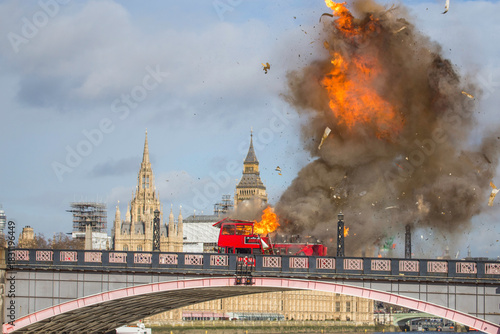 LONDON, UK -  7 2016.  A dramatic scene unfolds as a red double-decker bus explodes on Lambeth Bridge, with the iconic Parliament buildings in the background. 
