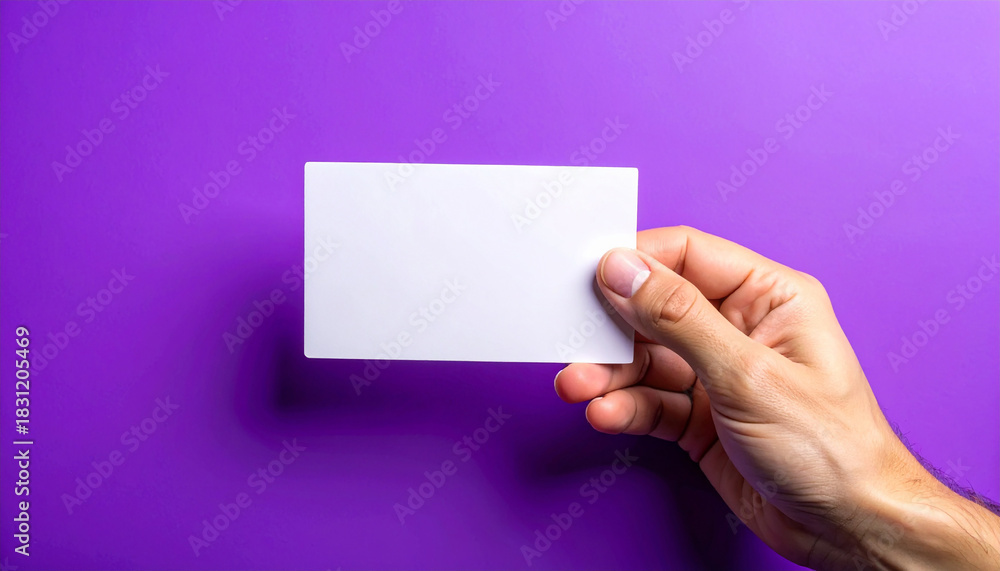 Fototapeta premium Hand holding blank card, vibrant purple background, minimalistic and clean presentation. Mock-up.