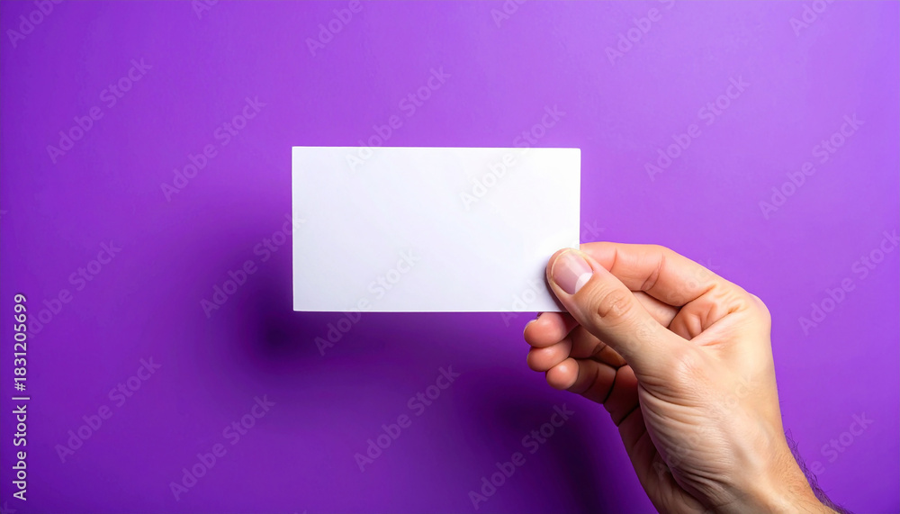 Fototapeta premium Hand holding blank card, vibrant purple background, minimalistic and clean presentation. Mock-up.