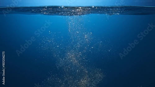 Bubbles rise in deep blue water beneath the surface