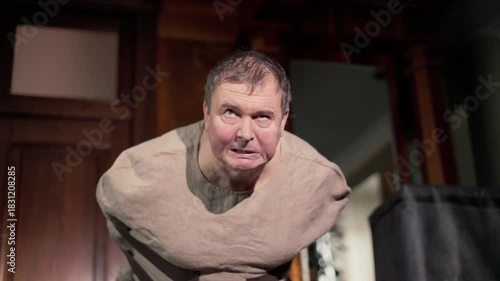 A tight straitjacket, a gray fabric that suffocated and bound the man like shackles.A sick older man is having a delirium tremens attack, he is being held bound in a straitjacket.