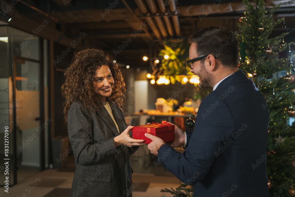 Fototapeta premium Colleagues exchanging holiday gifts during office christmas celebration