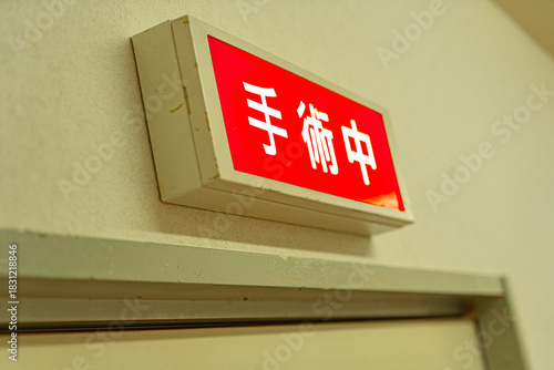 手術中を示す赤い警告ランプが医療施設の出入口に点灯している様子／Red “In Surgery” warning light illuminated at a medical facility entrance