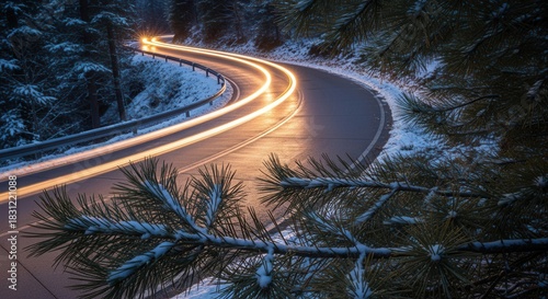 Curved snowy road with car light trails through pine forest at dusk