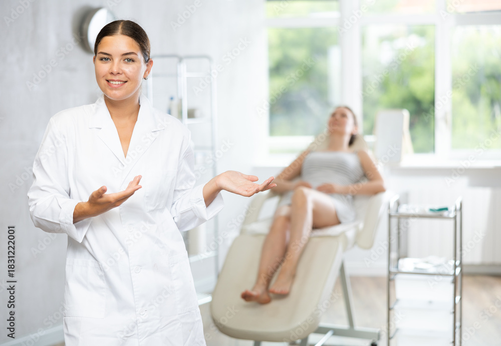 Obraz premium There is medical employee in hospital office. Unrecognizable patient sitting in chair in background. Private outpatient practice. Individual approach to treatment