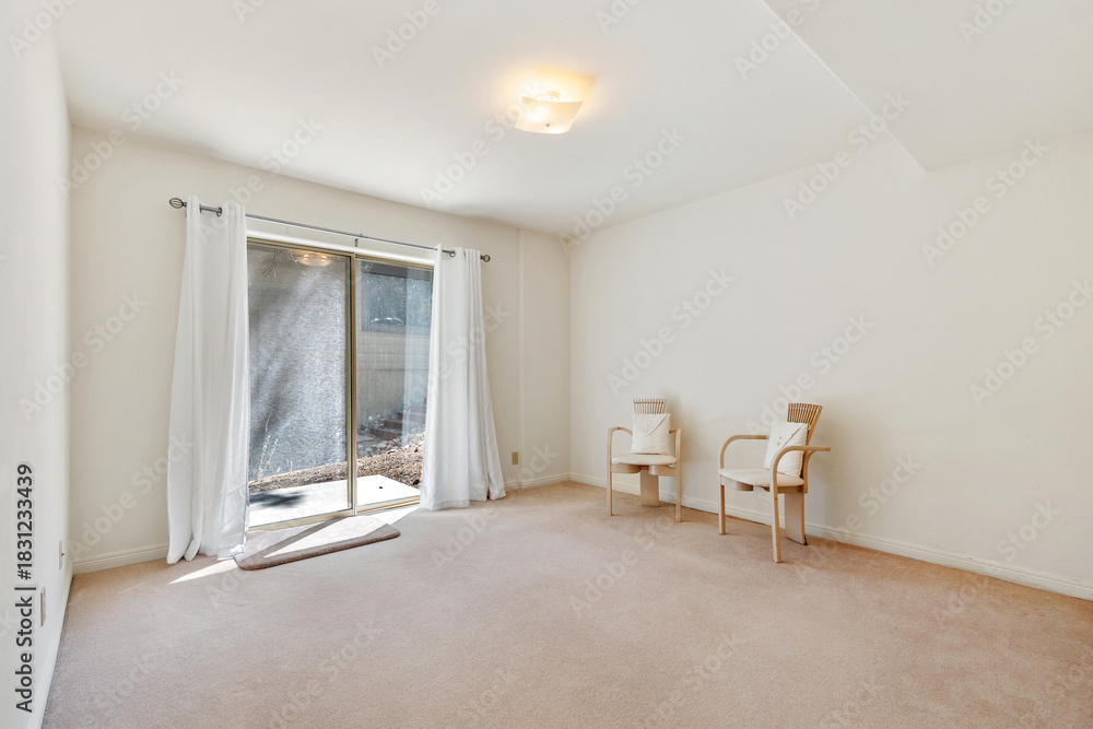 Fototapeta premium An empty living room with two chairs and a sliding glass door