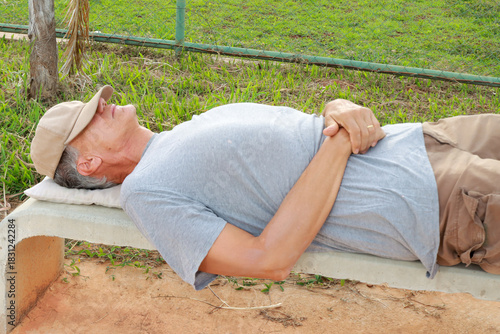 Older Homeless Man taking a nap on a Park Bench