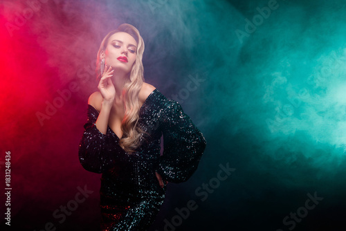 Elegant young woman in a glamorous sequined black dress posing confidently against a colorful smoky background