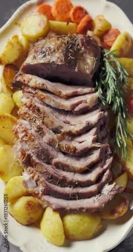 freshly baked pork neck tenderloin and baked potatoes on big white plate, food closeup