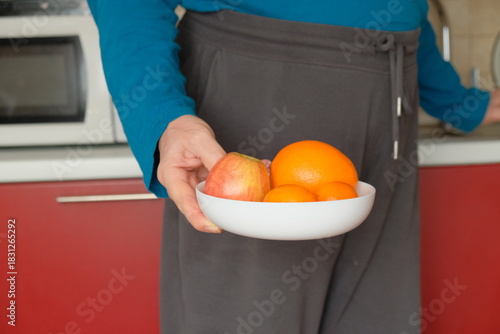 Man in the kitchen holding pepper in his hand, picking up other products and objects