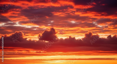 A breathtaking natural display of vibrant sunset clouds painted across the horizon, showcasing the fiery hues of dusk and the serene beauty of the evening sky