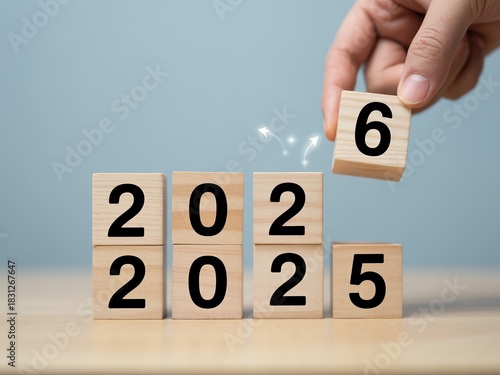 Silhouette anniversary celebrate countdown wooden cube blocks forming year change from 2025 to 2026 with hand flipping block in soft light New Year 2026 Concept