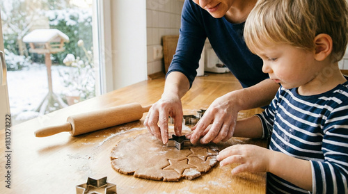 Mother and son making cookies together in a warm kitchen with winter view, family time activity