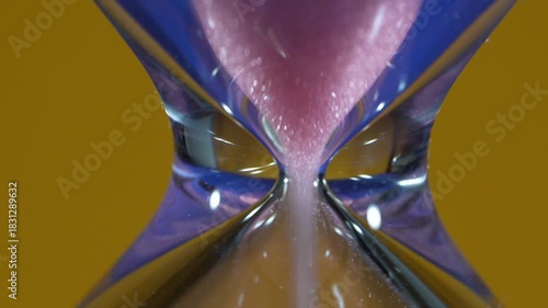 Hourglass, detail of the pink sand passing through the narrow, constricted tube.