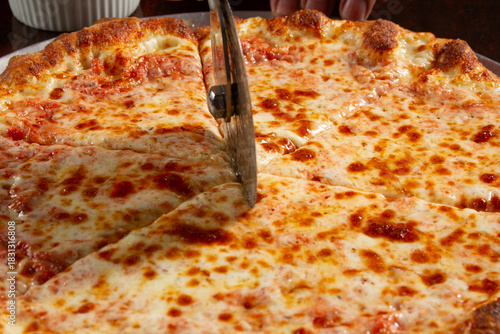 A view of a pizza slicer running through a cheese pizza.