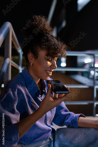 Woman smiles while using voice command on her phone.