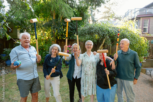 Seniors in a backyard playing croquet and laughing together