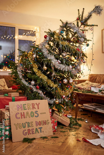 Chaotic Christmas living room with tilted tree & colorful sign. Great for humorous holiday marketing, greeting card concepts, social media posts & lifestyle branding.