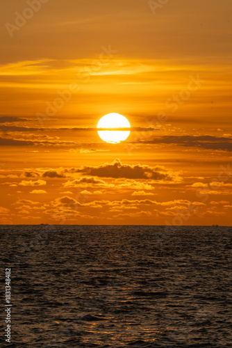 Golden Ocean Sunset with Dramatic Clouds. big Sun over the sea during a sunset with the sky coloured orange.