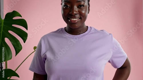 Young woman with plant in studio setting with soft lighting and pink background