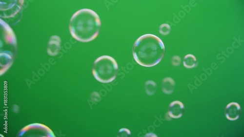 transparent green soap bubbles floating on green screen