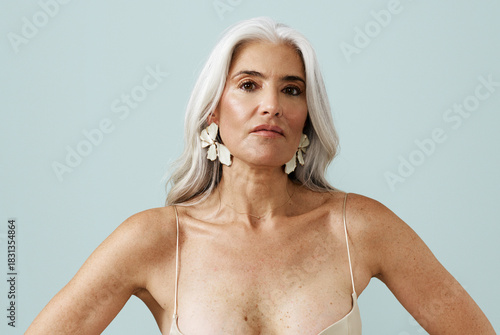 Confident Woman With Long Silver Hair Poses Against a Light Backdrop
