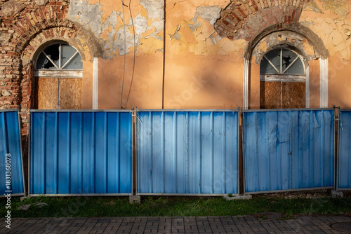Construction fence in front of a building in need of renovation
