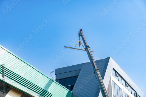 Obraz na płótnie Mobile crane lifting a steel beam for roof installation on a modern industrial or commercial building