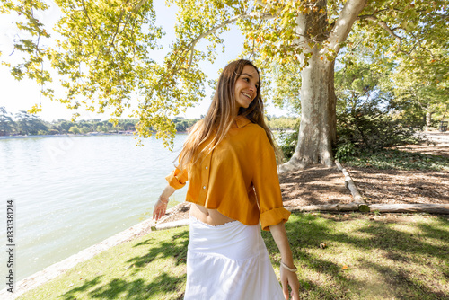 Young woman dancing freely in park in sunlight 