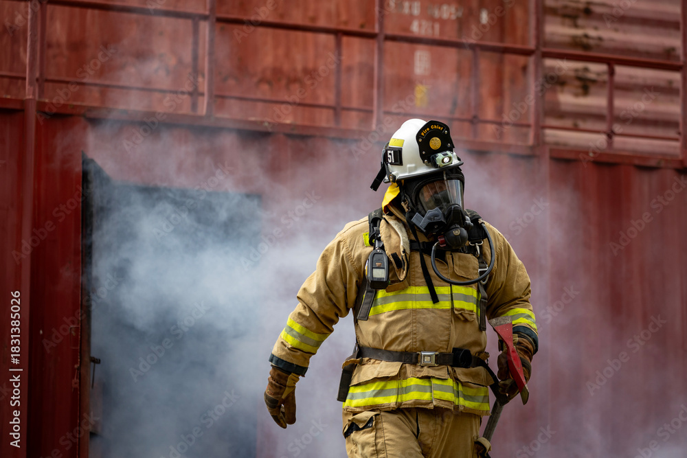 Fototapeta premium Portrait of firefighter in fireproof clothe walking out of the burning building full of ash and smoke for fire extinguish risk rescue mission and accident management concept