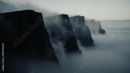 Dark cliffs emerge from the fog in a dramatic, atmospheric landscape