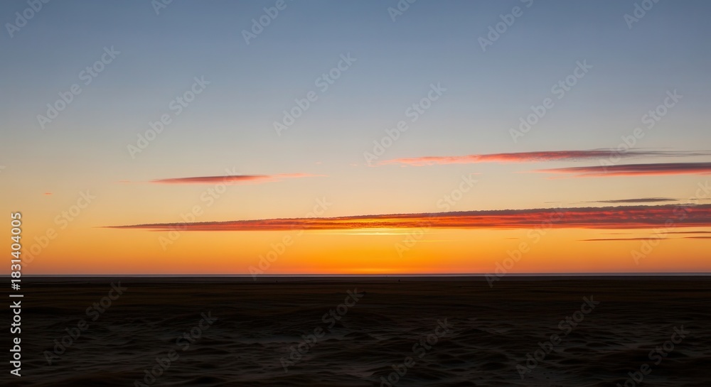 Naklejka premium Horizon line divides vibrant sunset colors above dark, textured terrain