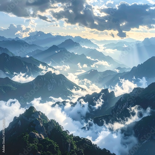 Sun rays stream down over layered mountain peaks and clouds